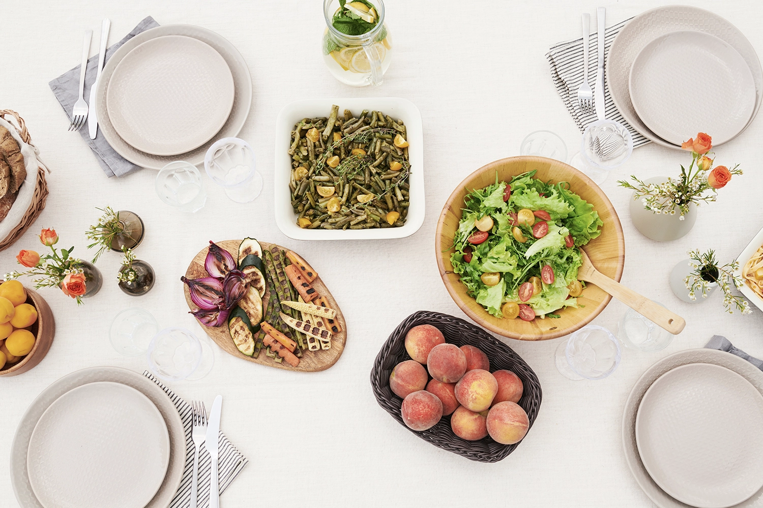 bowls and plates filled with salad, roasted vegetables and various types of fruit on a table